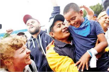  ??  ?? A man and his son, members of a caravan of migrants from Central America, react near the San Ysidro checkpoint as the first fellow migrants entered US territory to seek asylum in Tijuana, Mexico. — Reuters photo