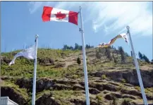  ?? RON SEYMOUR/The Daily Courier ?? Framed by Mount Boucherie, flags outside the West Kelowna city hall offices snap briskly in a stiff breeze Sunday afternoon.