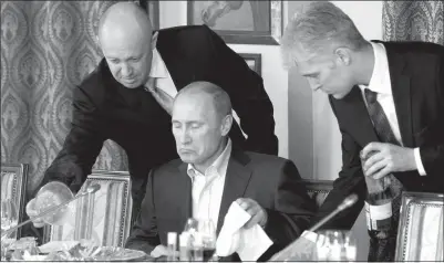  ?? MISHA JAPARIDZE / ASSOCIATED PRESS FILE (2011) ?? Vladimir Putin, center, is served dinner at a restaurant outside Moscow.