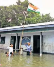  ?? HT ?? A teacher and students of a flooded school in Assam unfurl the tricolour to mark the Independen­ce Day on Tuesday.
