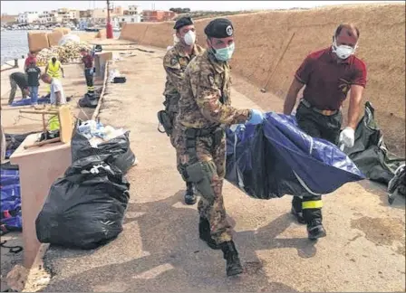  ??  ?? GRIM RECOVERY: The body of one of the drowned migrants is unloaded at the Sicilian port of Lampedusa as rescue efforts continued.
Picture: Reuters