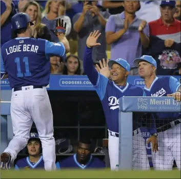  ?? AP PHOTO/MARK J TERRILL ?? Los Angeles Dodgers’ Logan Forsythe (left) is congratula­ted by manager Dave Roberts (center) and coach Bob Green after hitting a solo home run during the fourth inning of a baseball game against the Milwaukee Brewers, Friday, in Los Angeles.