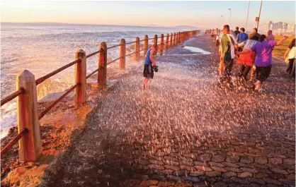  ??  ?? This file photo shows a child sprayed by a wave on the promenade, a popular tourist hotspot near the city of Cape Town, South Africa. — AP Photos