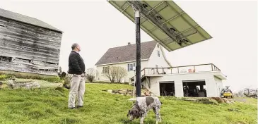  ?? Ian Thomas Jansen-Lonnquist/Bloomberg file photo ?? A customer inspects a solar panel that is linked to a Tesla Powerwall at a home in Monkton, Vermont, in 2016. Tesla produces the Powerwall — a home battery that stores solar energy.