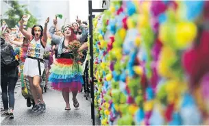  ?? RICHARD LAUTENS/TORONTO STAR ?? People marched alongside a colourful wall of flowers at Toronto's Pride Parade.