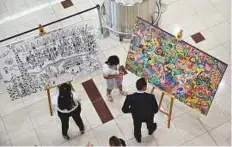  ?? Virendra Saklani/Gulf News ?? Visitors look at artworks created by people with special needs following the launch of the artDXB initiative at Dubai Airport’s Terminal 3 yesterday.