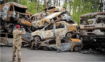  ?? EMILIO MORENATTI THE ASSOCIATED PRESS FILE PHOTO ?? A Ukrainian soldier poses next to cars destroyed in Irpin, near Kyiv, last week. In the face of the Russian invasion, militariza­tion is being amplified as a call for more upgraded weapons, Henry A. Giroux writes.