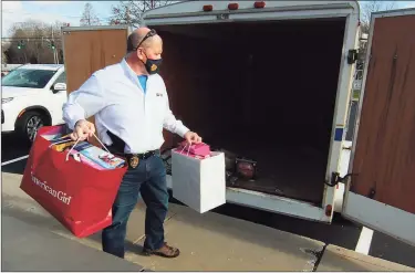  ?? Christian Abraham / Hearst Connecticu­t Media ?? Clinton Police Department’s Chief Vincent DeMaio places bags of donated gifts into a trailer at police headquarte­rs in Clinton.