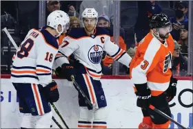  ?? MATT SLOCUM — THE ASSOCIATED PRESS ?? Edmonton Oilers’ Connor McDavid, center, celebrates with Zach Hyman, left, as Flyers defenseman Keith Yandle skates away during the third period Tuesday night at Wells Fargo Center.