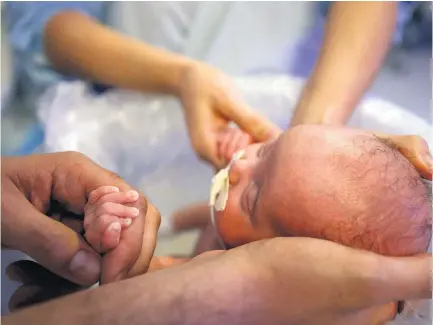  ?? FOTOS JF DIORIO/ESTADÃO ?? Ofurô. Mãe e pai dão banho de balde no pequeno Lucca na UTI neonatal; bebê teve alta após 110 dias de internação