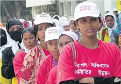 ??  ?? Women in Bangladesh wear T-shirts and caps with messages about safe migration on Internatio­nal Migration Day.