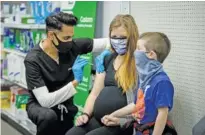  ?? CHORUS MEDIA GROUP VIA AP ?? Skippack Pharmacy owner and pharmacist Mayank Amin administer­s vaccine to Aubrie Cusumano while son Luca looks on Feb. 11 Skippack, Pa.