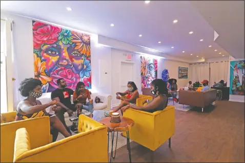  ?? (AP/Gerald Herbert) ?? Patrons relax over cocktails in the velvet chairs of DJ Johnson’s NOLA Art Bar in New Orleans on June 23. In mid-March, the city ordered all bars to close to avoid the spread of the coronaviru­s. On June 13, Johnson was able to start seating diners inside the gallery at half capacity. He makes constant rounds of the room, distributi­ng hand sanitizer. Gradually, customers are beginning to trickle in. “It’s discouragi­ng. But the only thing that kept me going is, there is no quit,” he said.