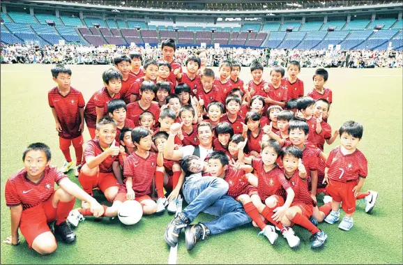 ??  ?? This handout picture released and taken on July 23 from MTG shows Portuguese football star Cristiano Ronaldo (center), posing with Japanese children during a football clinic in Nagoya in Aichi prefec
ture, central Japan. Ronaldo is currently on a...