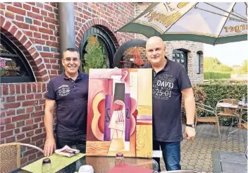  ?? RP-FOTO: HAHN ?? Jörg Savio (r.) und Antonio Ferreira mit einem Bild von Savios Mutter Jutta Musiol-Savio, frei nach Picassos „Die aufgehängt­e Geige“aus dem Restaurant. Das Gemälde zieht mit um in die Burg Wassenberg.