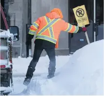  ??  ?? A city worker puts up no-parking signs on Cypress Street on Sunday as the massive cleanup of snow from Montreal streets got underway.