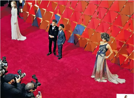  ??  ?? Lining up on the red carpet, from left, Isabelle Huppert in Armani, Moonlight actors Jaden Piner and Alex R Hibbert, and Halle Berry in Versace