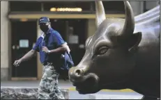  ?? ASSOCIATED PRESS ?? A MAN WEARING A MASK passes the Charging Bull statue Tuesday in New York’s financial district. More sharp declines for big tech stocks dragged Wall Street toward a third straight loss on Tuesday.