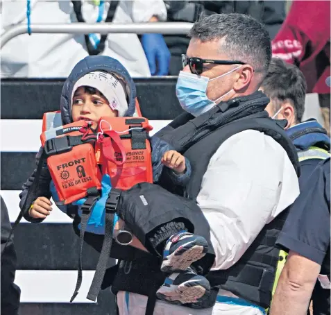  ??  ?? A young child among a group of people thought to be migrants crossing from France is brought in to Dover by Border Force officers, following a small boat incident in the Channel