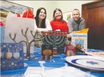  ?? ALLEN MCINNIS ?? Liberty Budman, from left, Amy Fish and David Budman show off the gifts they purchased for a new type of Hanukkah exchange.