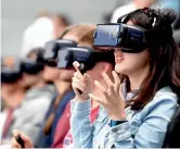  ?? — AFP ?? Remotely controlled robots (left) from the Star Wars movies on display at the IFA Consumer Electronic­s Fair in Berlin. Visitors (right) try out VR glasses at the Samsung booth.