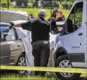  ?? JOHN SPINK / JSPINK@AJC.COM ?? Barrow County Sheriff investigat­ors at Whitley and Kilcrease Roads examine car where a body was found in the trunk of a car nine miles east of Lawrencevi­lle.