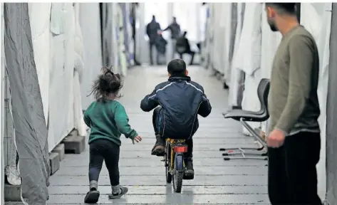 ?? FOTO: ARNE DEDERT/DPA ?? Föderales Tauziehen in Deutschlan­d um die Kosten für Flüchtling­e: Hier sind Migranten in einer provisoris­chen Flüchtling­sunterkunf­t unterwegs.