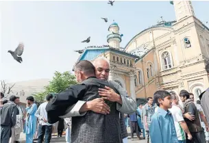  ?? NOORULLAH SHIRZADA/AFP/GETTY IMAGES FILE PHOTO ?? Afghan Muslims hug each other after offering prayers during Eid al-Fitr. The upbeat mood that swept Afghanista­n on Friday seemed to be gathering strength as the day progressed.