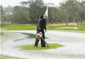  ?? Eric Risberg / Associated Press ?? After a brief hail storm, a greenskeep­er uses a leaf blower to clear the second green. Play was suspended for about two hours because of the hail.