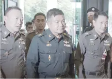  ?? — AFP ?? This file photo taken on June 3, 2015 shows Thai Army Lieutenant General Manas Kongpan (C) being surrounded by police officers as he turns himself in at the police headquarte­rs in Bangkok.