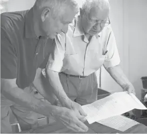  ?? JESSICA HILL/AP ?? Dave Ware, left, and his father, Fred Ware, look over a deed and copy of a covenant for their home in Manchester.