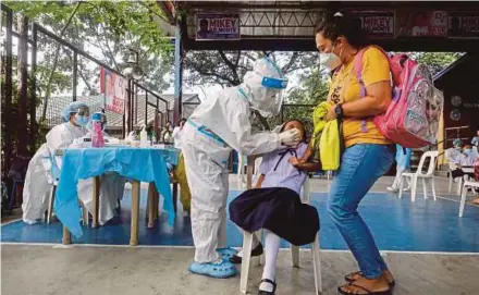  ?? EPA PIC ?? A student (seated, centre) undergoing a Covid-19 antigen test, as her mother (right) looks on, before attending an in-person class at an elementary school in Quezon City, Metro Manila, Philippine­s, yesterday.