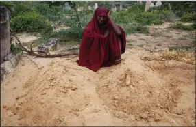  ?? (AP/Farah Abdi Warsameh) ?? Fatuma Abdi Aliyow sits Saturday at the graves of her two sons, who died of malnutriti­on-related diseases last week, at a camp for the displaced on the outskirts of Mogadishu, Somalia.