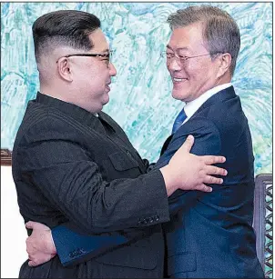  ?? AP ?? North Korean leader Kim Jong Un (left) and South Korean President Moon Jae-in embrace Friday after signing a joint statement setting a goal of a nuclear-free Korean Peninsula during their meeting at the border village of Panmunjom, South Korea.