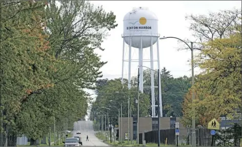  ?? CHARLES REX ARBOGAST ?? A lone resident of Benton Harbor, Mich., walks across Britain Street Oct. 22, near the city’s water tower in Benton Harbor. The water system in Benton Harbor has tested for elevated levels of lead for three consecutiv­e years. In response, residents have been told to drink and cook with bottled water and the state has promised to spend millions replacing lead service lines.