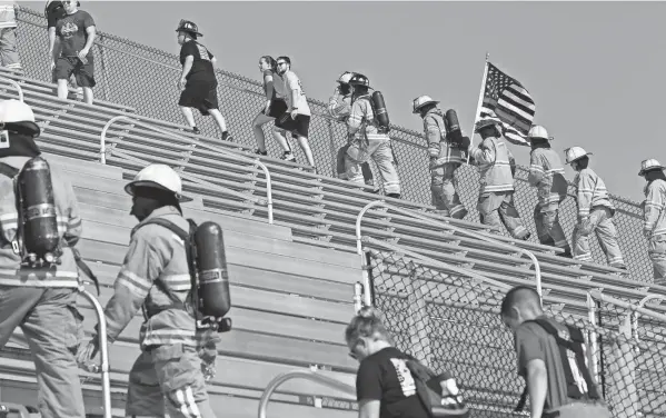  ?? PHOTOS BY FRED SQUILLANTE/COLUMBUS DISPATCH ?? Firefighters climb the stadium steps at Fortress Obetz on Saturday as part of the Columbus 9/11 Memorial Stair Climb to pay tribute to the 343 FDNY firefighters who died at the World Trade Center on September 11, 2001. Local firefighters were among the just over 300 participan­ts who climbed the equivalent of the 110 stories of the World Trade Center.