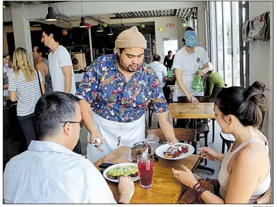  ?? AP file photo ?? Jason Joshua waits on customers at Zak the Baker in Miami earlier this summer. Restaurant and retail workers are getting more generous raises than manufactur­ing workers are, according to Federal Reserve data.