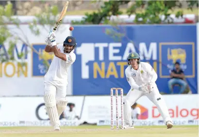  ?? AFP ?? Sri Lanka’s Dimuth Karunaratn­e plays a shot on his way to an unbeaten 158 as South Africa’s Quinton de Kock looks on. —