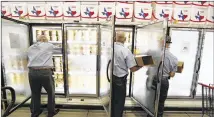  ?? STEVE GONZALES / HOUSTON CHRONICLE ?? Blue Bell workers Freddie Hugo (from left), Rickey Seilheimer and Charlie Franke stock freezers with ice cream products early Monday in Brenham, the company’s base.