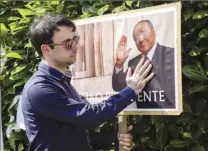  ?? AP photo ?? A man poses next to a poster of Silvio Berlusconi outside the latter’s residence in Arcore, near Milan on Monday. Berlusconi died Monday, according to Italian media. He was 86.