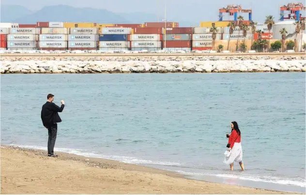  ?? R euters ?? ±
Tourists take pictures on a beach in a port in Malaga, Spain.