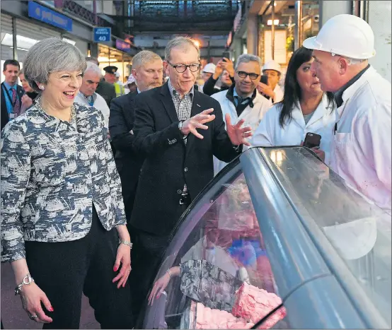  ??  ?? Theresa May and her husband Philip talking to a butcher in London’s Smithfield Market early yesterday at the start of the last day’s campaignin­g