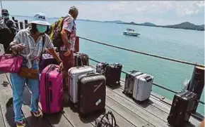  ?? AFP PIC ?? In this picture taken in August, tourists are travelling on a ferry pick up their luggage on arrival at a jetty on Koh Samui in the Gulf of Thailand.