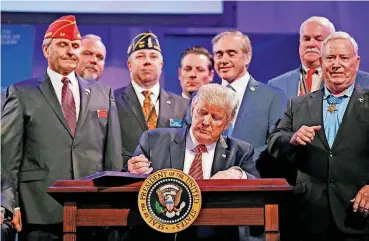  ?? [AP PHOTO] ?? President Donald Trump prepares to sign the Veterans Appeals Improvemen­t and Modernizat­ion Act on Wednesday at the National Convention of the American Legion in Reno, Nev.