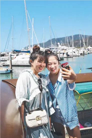  ?? Picture: BRENDAN RADKE ?? PROMOTING BRAND CAIRNS: Yingwen Jin and Yidie Xu, from China, take some holiday photos at the Cairns Marlin Marina, boosting tourism in Far North Queensland.