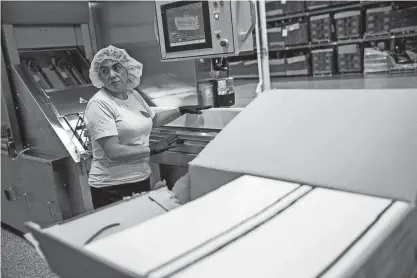  ?? CODY SCANLAN/HOLLAND SENTINEL ?? Boxed Water employees work to prepare cartons before they are fed into an automated machine at the company’s Holland, Mich., plant.