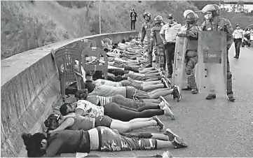  ?? — Reuters photos ?? Detainees lie on the street after being rounded out for looting during an ongoing blackout in Caracas.