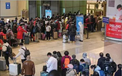  ?? (AFP) ?? Mask-clad passengers wait in a line at the railway station in Wuhan, on Saturday, after travel restrictio­ns into the city were eased.