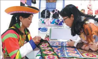  ?? LIU LEI / XINHUA ?? A Tu ethnic woman shows embroidery techniques to a tourist at an intangible cultural heritage exhibition in Hohhot, Inner Mongolia autonomous region, on Wednesday. The exhibition, which started on Friday and ends on Thursday, features more than 180 intangible cultural heritage items representi­ng all ethnic groups in China.