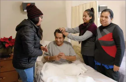  ?? CATHIE COWARD, THE HAMILTON SPECTATOR ?? Jesus Rosas Flores with his wife, Teresa, right, and daughters Carmen and Maria, lovingly tidying his hair for a family photo.